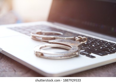 Close Up Of Police Handcuff On Notebook Keyboard Cybercrime Concept.