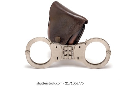 Close Up Police Iron Metal Steel Handcuffs With Rigid Intermediate Piece In Front Of Dark Leather Case Closed Wrist Locking Bars On White Background As Concept For Arrest And Imprisonment