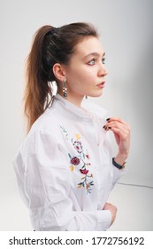 Close Up Portrait Of 20-25 Years Old Girl In A White Blouse. Beautiful Girl With A Tail Posing And Not Looking At The Camera