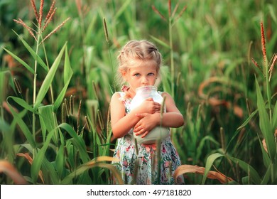 Close Up Portrait Of Adorable Blonde Little Girl With Blue Eyes. Cute Child Drinking A Milk From A Big Bank And Looking At Camera.Happy Childhood. Sunny Day. Pretty Kid Enjoying The Nature Outdoor.