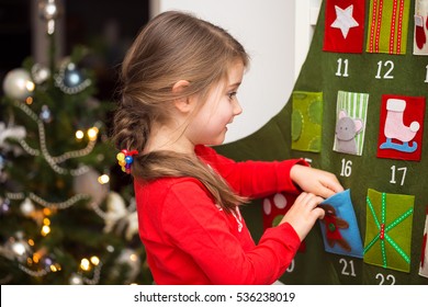 Close up portrait of adorable girl looking into the twenty-first pocket of advent calendar