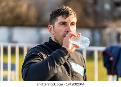 Close Up Portrait Of Adult Caucasian Man Standing Outdoor With Plastic Bottle Of Water Drinking - Male Amateur Athlete Drink During Rest At Outdoor Training In Sunny Day - Real People Copy Space