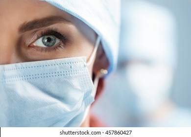 Close Up Portrait Of Adult Female Surgeon Doctor Wearing Protective Mask And Cap. Half Face Closeup. Healthcare, Medical Education, Emergency Medical Service And Surgery Concept