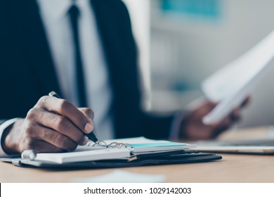 Close Up Portrait Of African, American Man's Hand Writing In Organizer, Planning His Week, Holding Pencil In Workplace, Workstation