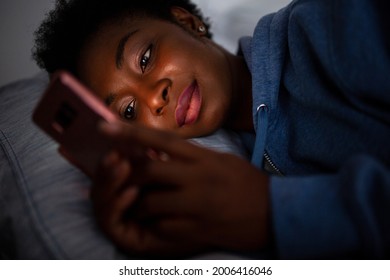 Close Up Portrait African American Woman Looking At Phone While In Bed