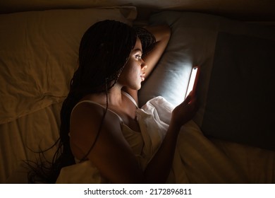 Close Up Portrait African American Woman Looking At Phone While In Bed.