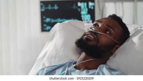 Close Up Portrait Of Afro-american Young Patient Feeling Unwell Lying In Hospital Bed. Black Sick Man Having Fever And Sweating Resting In Intensive Care Unit