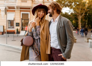 Close up portrait of amazing stylish couple in love  spending  romantic holidays in European city. Pretty blond woman in hat and casual dress smiling and looking on her handsome man with beard.