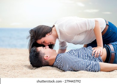 Close up portrait of Amorous teen couple playing around on beach. Teen couple laughing and having fun together. 