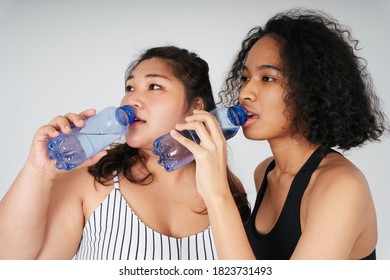 Close Up Portrait Of Asian Chubby And African Women Drinking Water From Bottle Together.