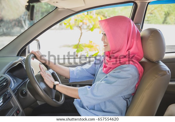 close up portrait of asian woman wearing hijab\
driving a car and hit the\
horn