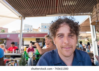 Close Up Portrait Of Attractive Forty Something Man Having Lunch At A Busy Restaurant In A European City.