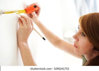 Close up portrait of attractive mature woman using measuring tape and pencil to mark the wall - Powered by Shutterstock