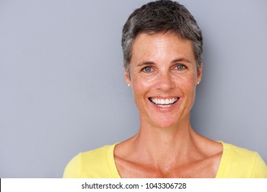 Close up portrait of attractive middle age woman smiling against gray background