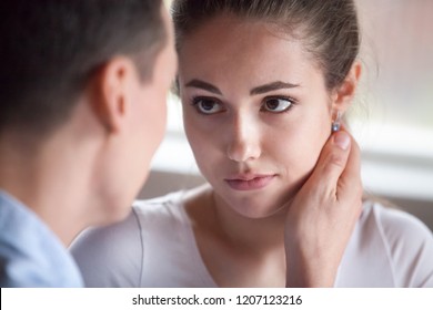 Close up portrait attractive millennial couple in love. Sulky upset wife looking at husband tender man touch face with hand beloved woman making peace and apologizes. Loving boyfriend calms girlfriend
