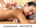 Close up portrait of attractive woman enjoying aromatic ayurveda pinda massage on back and shoulder.