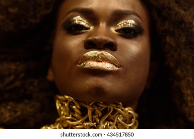 Close up portrait of an attractive young African woman with unique golden makeup