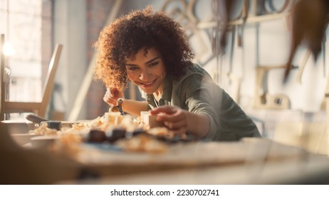 Close Up Portrait of an Attractive Young Artisan Carpenter Using Hand Plane to Shape a Wood Bar. Multiethnic Female Working on a Project in a Loft Studio with Tools on Walls. - Powered by Shutterstock