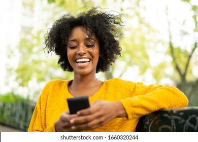 Close up portrait attractive young woman sitting outside looking at mobile phone