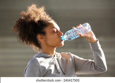 Close up portrait of an attractive young woman drinking water from bottle - Powered by Shutterstock