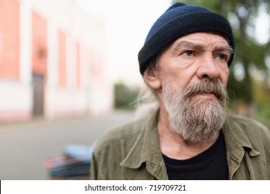 Close Up Portrait Of Beardy Old Man Outdoors. Homeless Man With Sad Look.