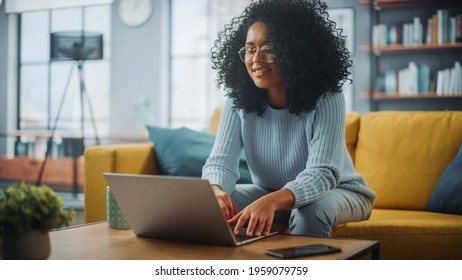 Close Up Portrait Of A Beautiful Authentic Latina Female In A Cozy Living Room Using Laptop Computer At Home. She's Browsing The Internet And Checking Videos On Social Networks And Having Fun.