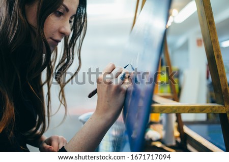 Close up portrait of beautiful and authentic young female artist or painter create art piece. Detailed work for personal creative project. Tattoo artist draws artwork