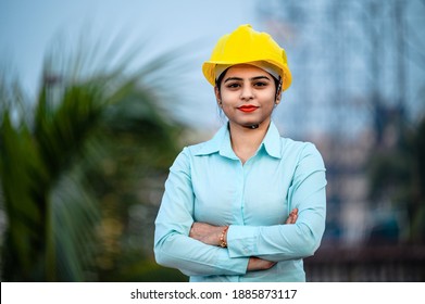 Close up portrait of beautiful female engineer wearing a protective helmet and looking at camera.