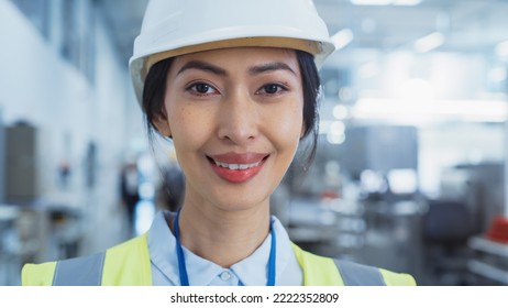 Close Up Portrait Of A Beautiful, Happy And Smiling Asian Female Engineer In White Hard Hat Standing At Electronics Manufacturing Factory. Successful Heavy Industry Specialist Posing For Camera.