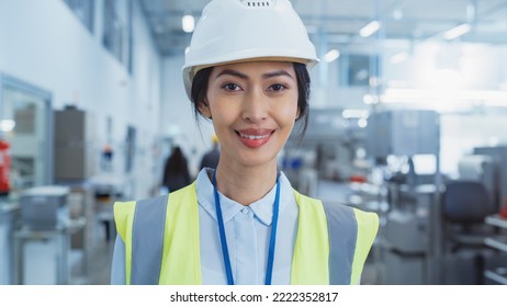 Close Up Portrait Of A Beautiful, Happy And Smiling Asian Female Engineer In White Hard Hat Standing At Electronics Manufacturing Factory. Successful Heavy Industry Specialist Posing For Camera.