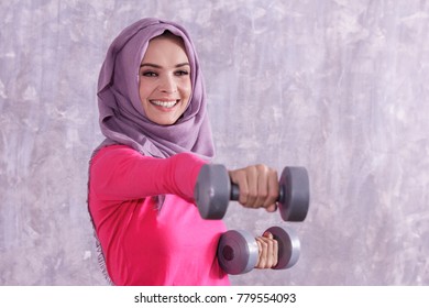 Close Up Portrait Of Beautiful Hijab Sporty Woman Workout Using Dumbbell With Concrete Wall On The Background