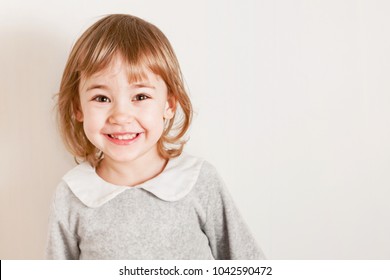 Close Up Portrait Of Beautiful Little Girl Smiles On A Light Background