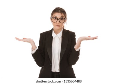 Close up portrait of a beautiful Puzzled woman wearing black business suit and glasses holding hands in air in confusion with the face expression I do not know, so what isolated on a white background.