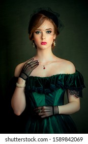 Close up portrait of a  beautiful red hair girl in a green vintage dress, jewelry and black veil on her face. Art work of romantic woman .Pretty tenderness model looking at camera.