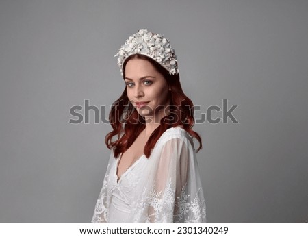 close up portrait of beautiful red haired model wearing elegant pearl wedding headdress on a studio background.