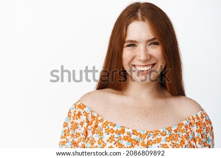 Close up portrait of beautiful redhead girl laughing and smiling, candid face of happy person, standing over white background