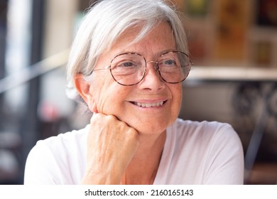 Close up portrait of a beautiful senior Caucasian woman with white short hair and eyeglasses as she looks thoughtfully away while sitting in coffee shop - Shutterstock ID 2160165143