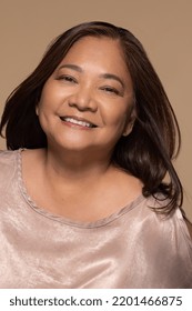 close up portrait of beautiful southeast Asian woman in her 50s smiling happy and posing on neutral background Stock Photo