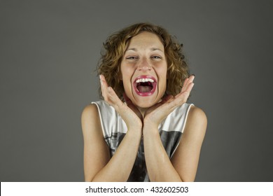 Close Up Portrait Of Beautiful Woman Brunette With Curly Hair With A Huge Smile Shoot In Studio, Isolated On A Grey Background