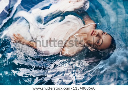 close up portrait of beautiful woman lying in water with fabric. Fashion concept