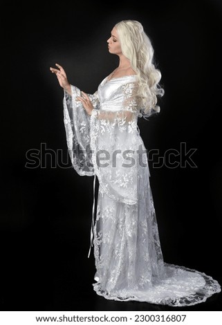 Close up portrait of beautiful women with long blonde hair, wearing white fantasy  princess  ball gown, standing pose walking away  in side profile. Isolated on black studio background.