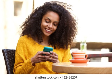 Close up portrait of beautiful young african american woman reading text message on mobile phone at coffee shop