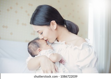 Close Up Portrait Of Beautiful Young Asian Mother Kissing Her Newborn Baby. Healthcare And Medical Love Lifestyle Motherâ??s Day Concept