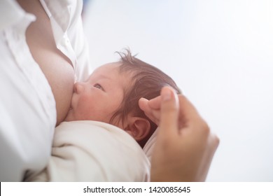 Close up portrait of beautiful young asian mother with her newborn baby While breastfeeding, copy space with bed in the hospital background. Healthcare and medical love, lifestyle mother's day concept