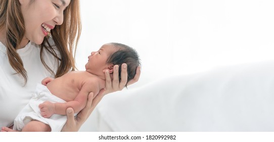 Close Up Portrait Of Beautiful Young Asian Mother With Newborn Baby. Side View Of A Young Woman Playing With Her Little Baby.