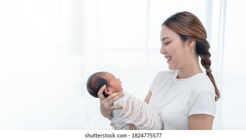 Close Up Portrait Of Beautiful Young Asian Mother With Newborn Baby. Side View Of A Young Woman Playing With Her Little Baby.