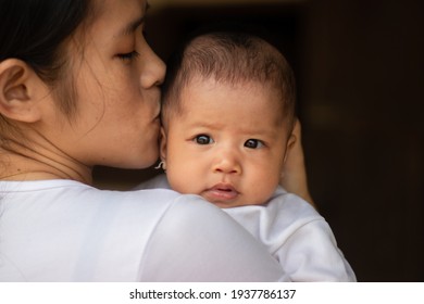 Close Up Portrait Of Beautiful Young Asian Mother Kissing Her Newborn Baby Outside The House