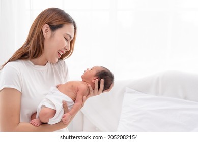 Close Up Portrait Of Beautiful Young Asian Mother With Newborn Baby. Side View Of A Young Woman Playing With Her Little Baby In Bed.