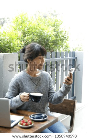 Close up portrait of beautiful young asian woman reading text message on mobile phone at coffee shop or home office. Selective focus. 