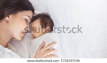 Close up portrait of beautiful young asian caucasian mother day girl kissing healthy newborn baby sleep in bed with copy space. Healthcare and medical love asia woman lifestyle mother's day concept
